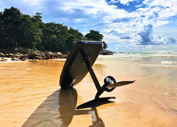 Foil board resting on a sandy beach.