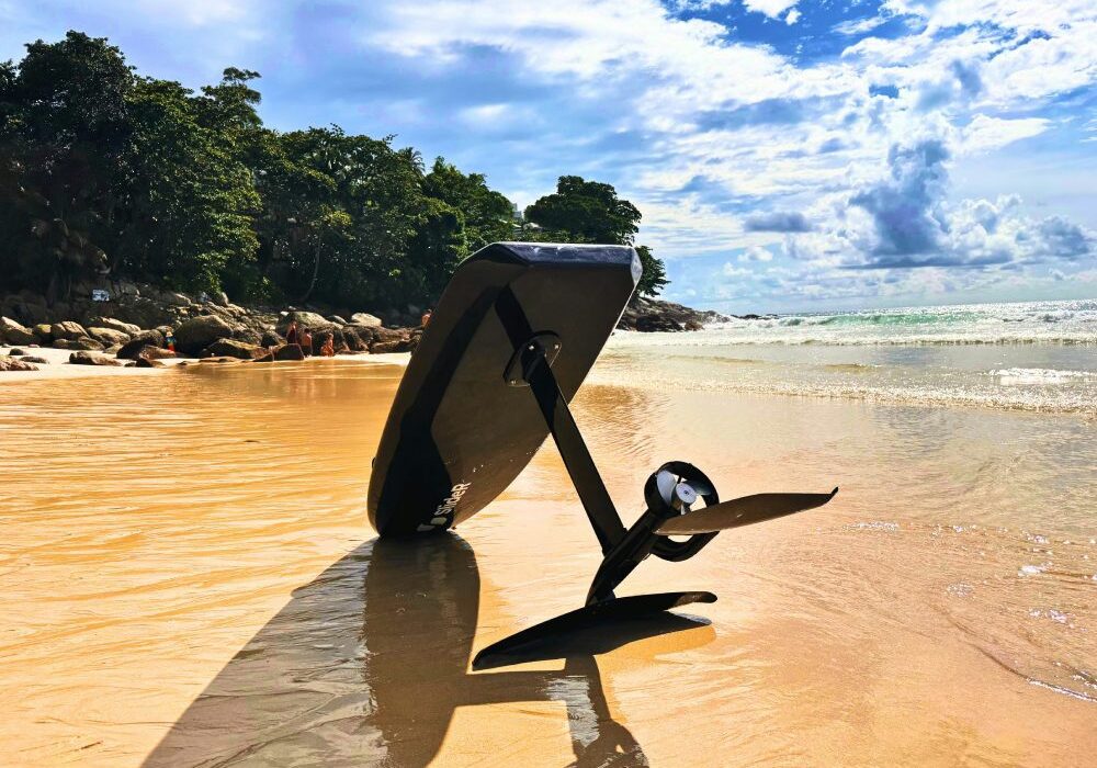 Foil board resting on a sandy beach.
